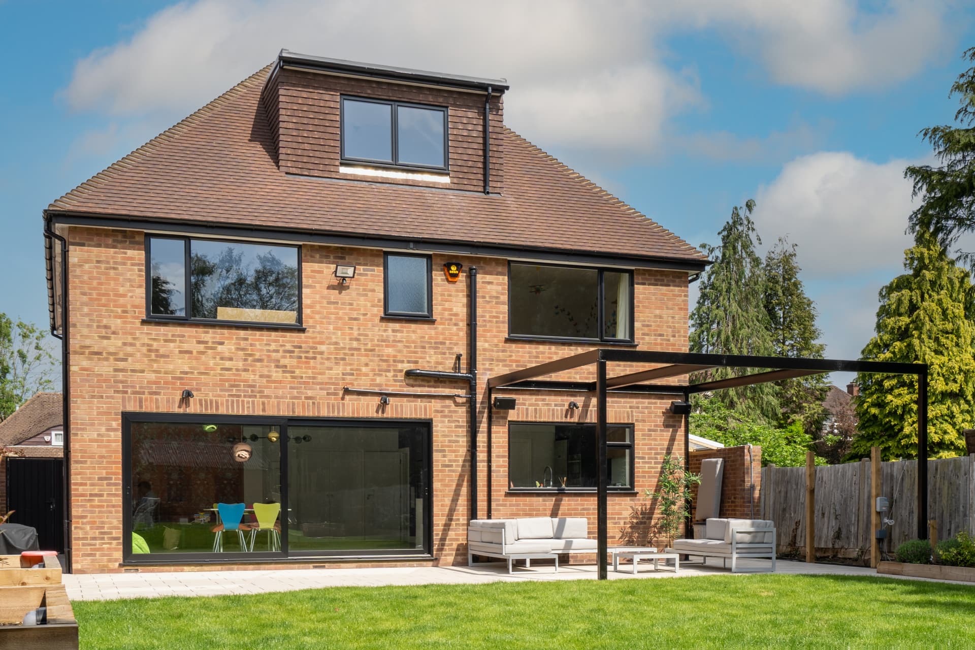The rear of a family home after an extension and loft conversion, opening onto a garden