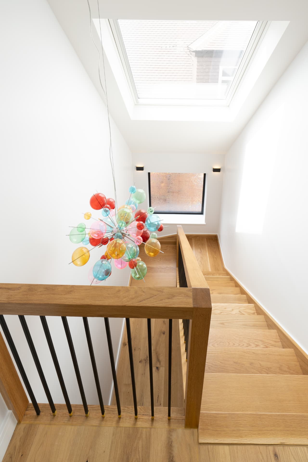 A bright stairwell with a rooflight above an oak staircase